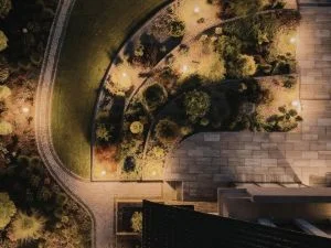 Aerial view of residential landscape with curved driveway, mature trees, and hardscape elements