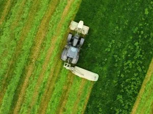 Aerial view of zero-turn mower cutting grass with professional striping pattern