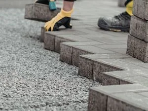 Permeable pavers being installed with gravel base and concrete edge borders