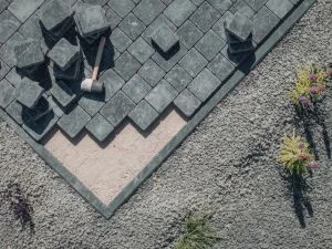 Geometric patterned paver walkway with charcoal and tan diamond design on concrete base